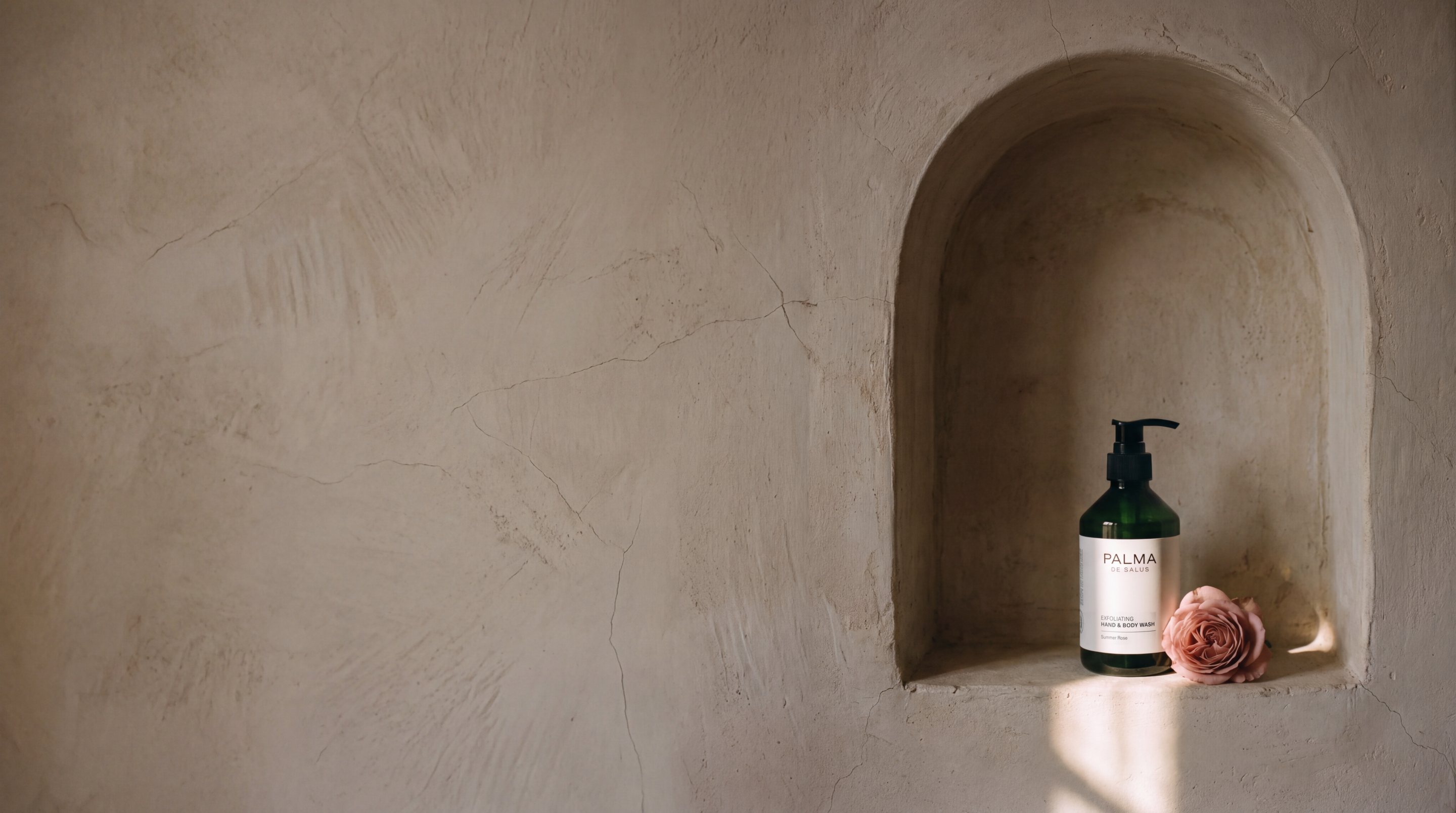 Palma de Salus Summer Rose Exfoliating Hand & Body Wash with a garden rose in a sunlit plaster niche